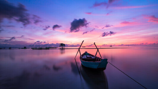Zachód słońca nad wodą z łódką